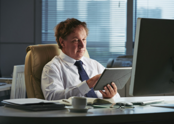 homem trabalhando em um computador e em um tablet